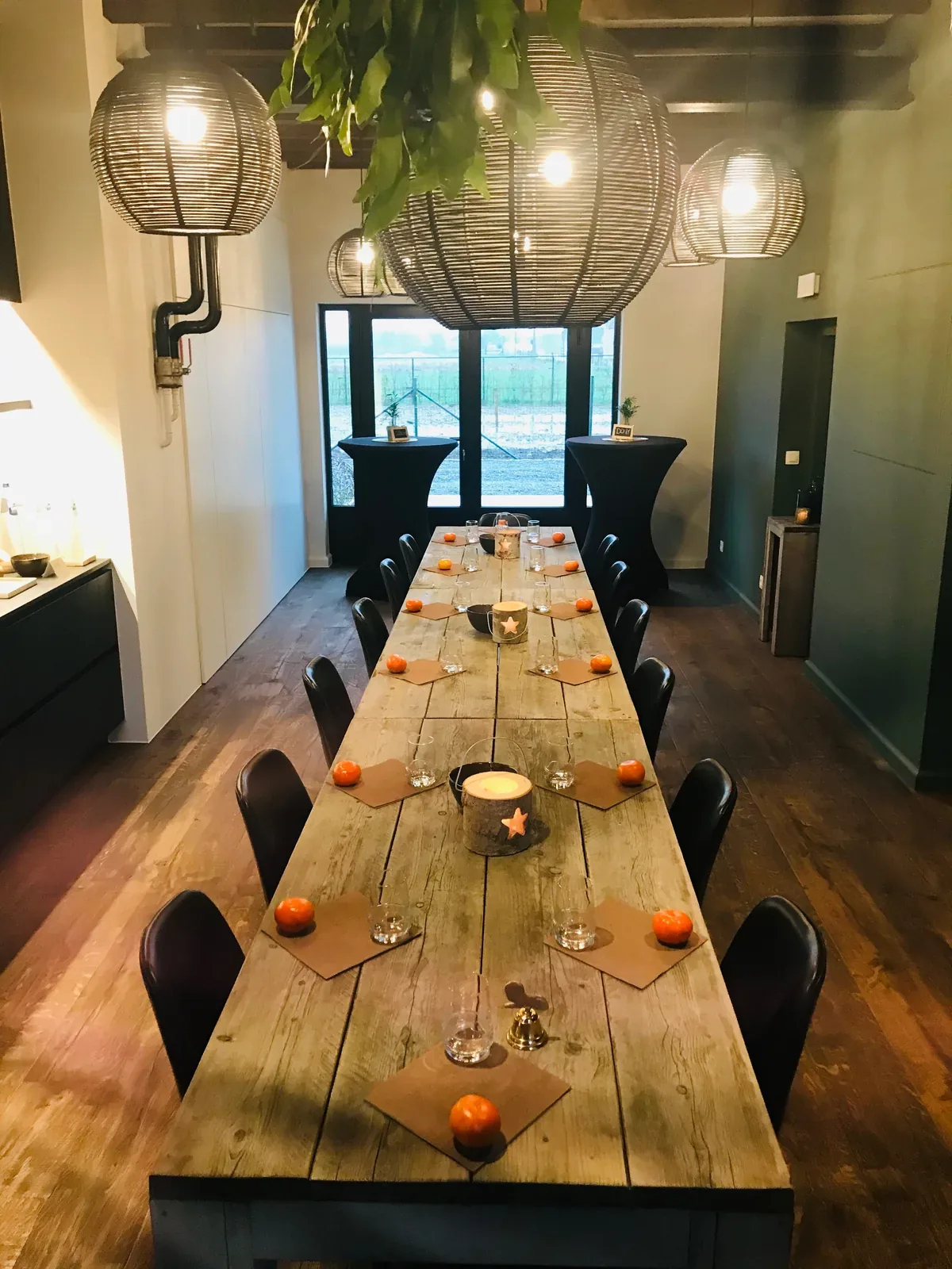 De tuinkamer met een lange houten tafel en hanglampen