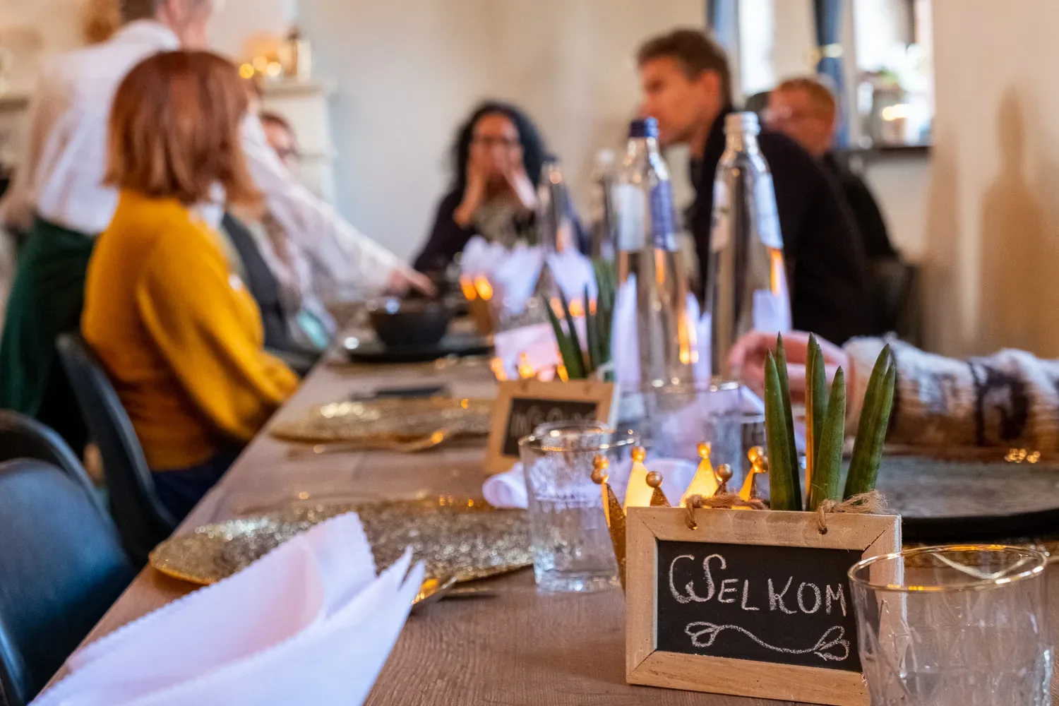 Gasten in gesprek aan een lange gedekte tafel bij Huis van Mem in Halen