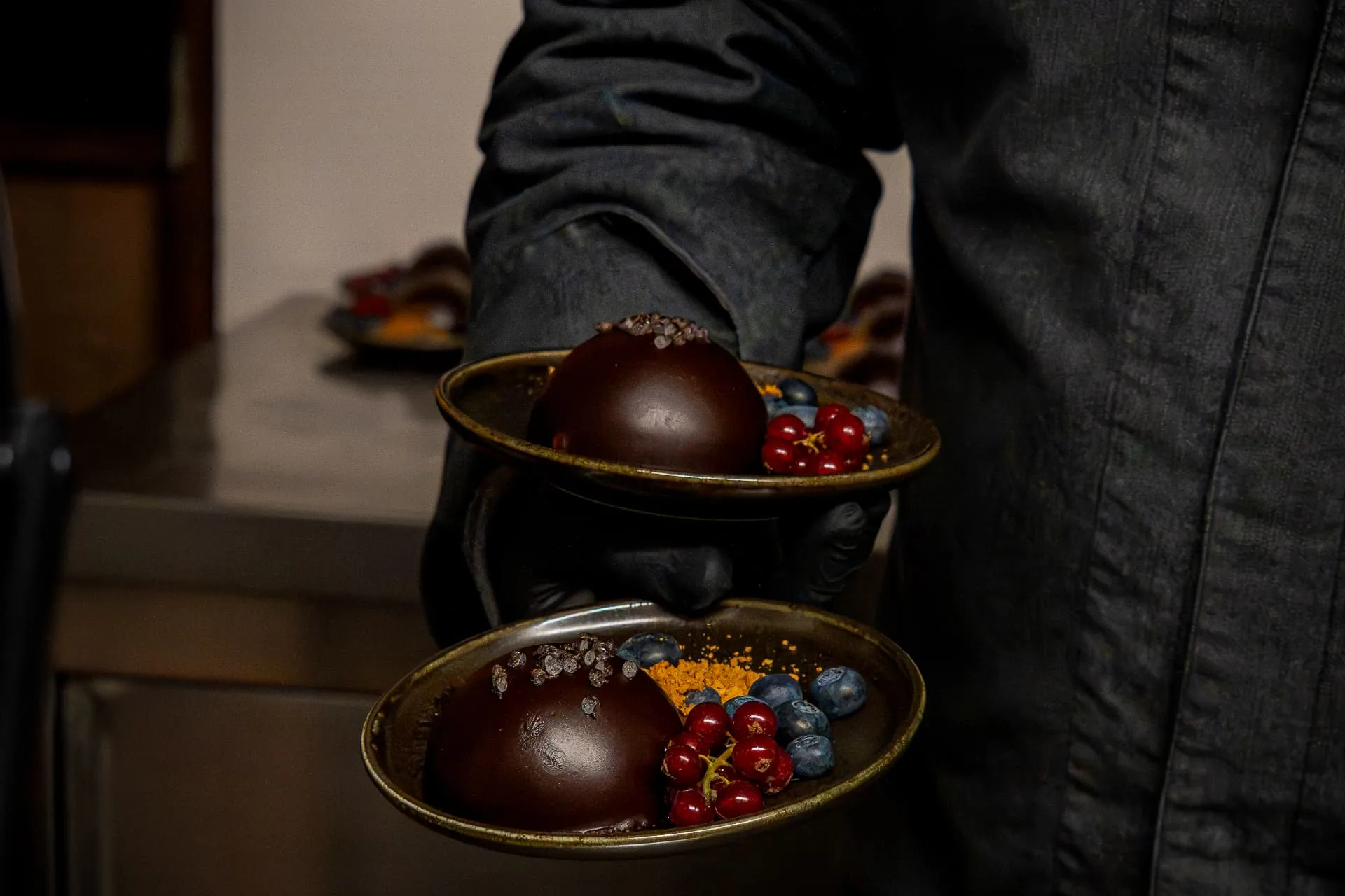 Gedekte borden met chocoladedomes, rode bessen en bosbessen in de keuken van Huis van Mem