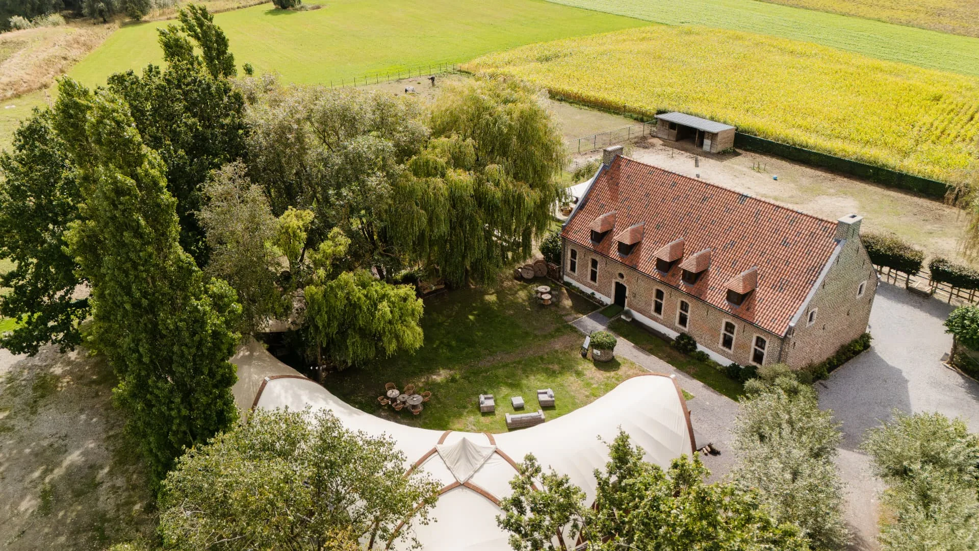 Luchtopname van Huis van Mem met de historische hoeve, het paviljoen, de tuin en het omliggende landschap